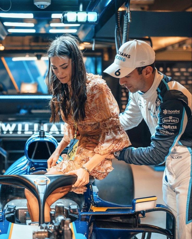 a man and woman working on a race car