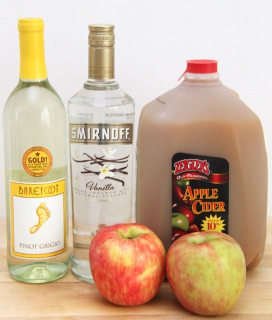 apples, an apple cider, and two bottles of alcohol sit on a table