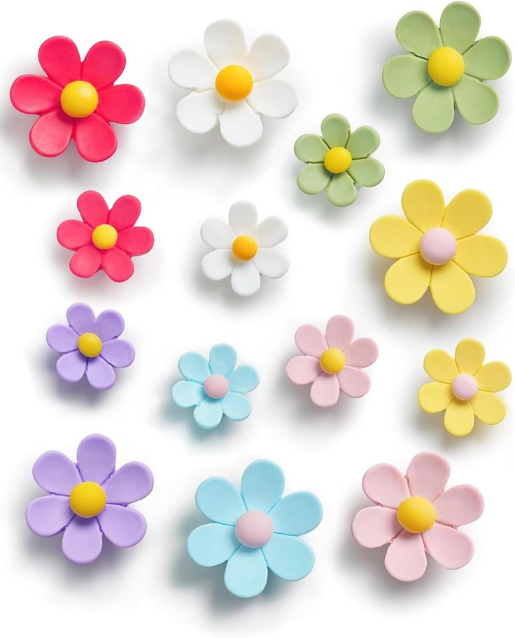 several different colored plastic flowers on a white surface