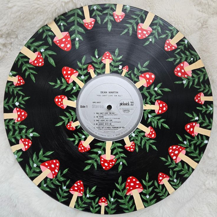 a black record with red mushrooms and green leaves on it