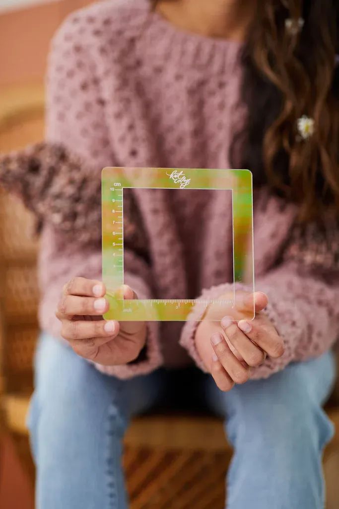 a woman sitting on a chair holding up a small square frame with the word love in it