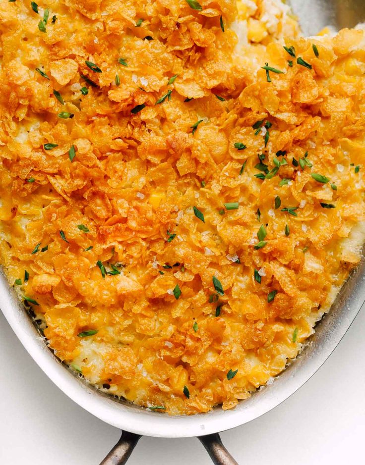 a cheesy casserole in a white dish with two serving utensils