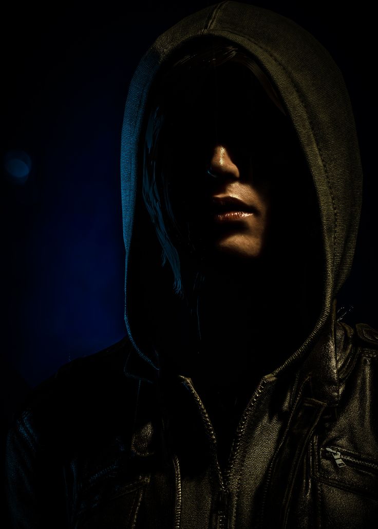 a man wearing a hooded jacket in the dark