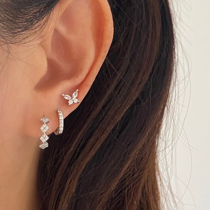 a woman's ear is shown with three small diamonds on the back of it