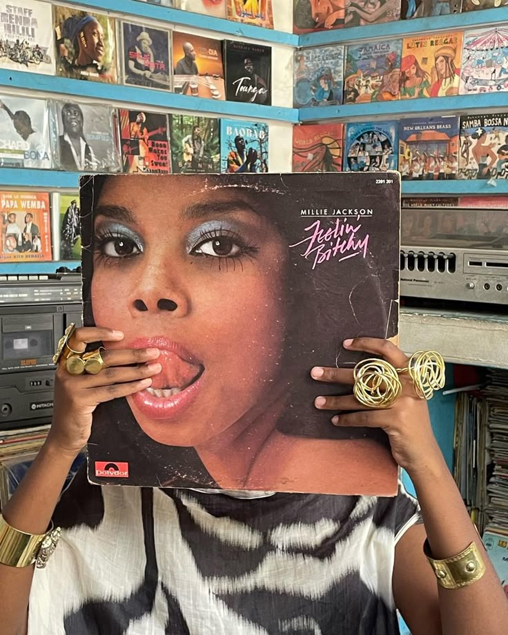 a woman holding up a record in front of her face with an album on it