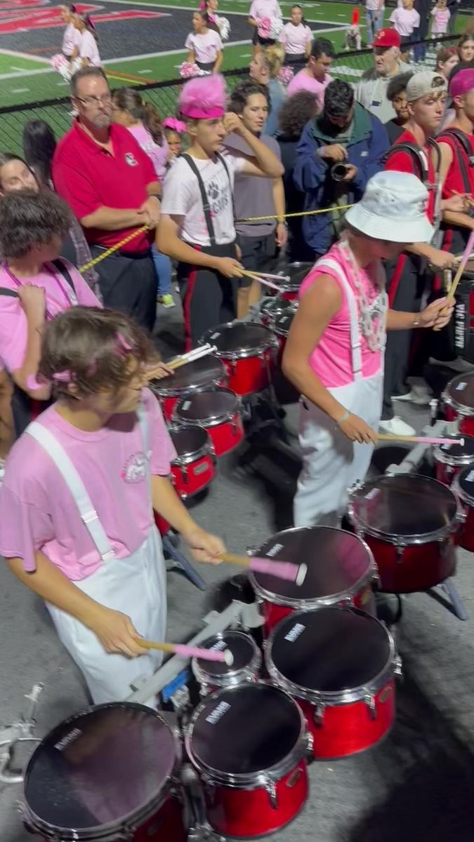 a group of people in pink shirts playing drums