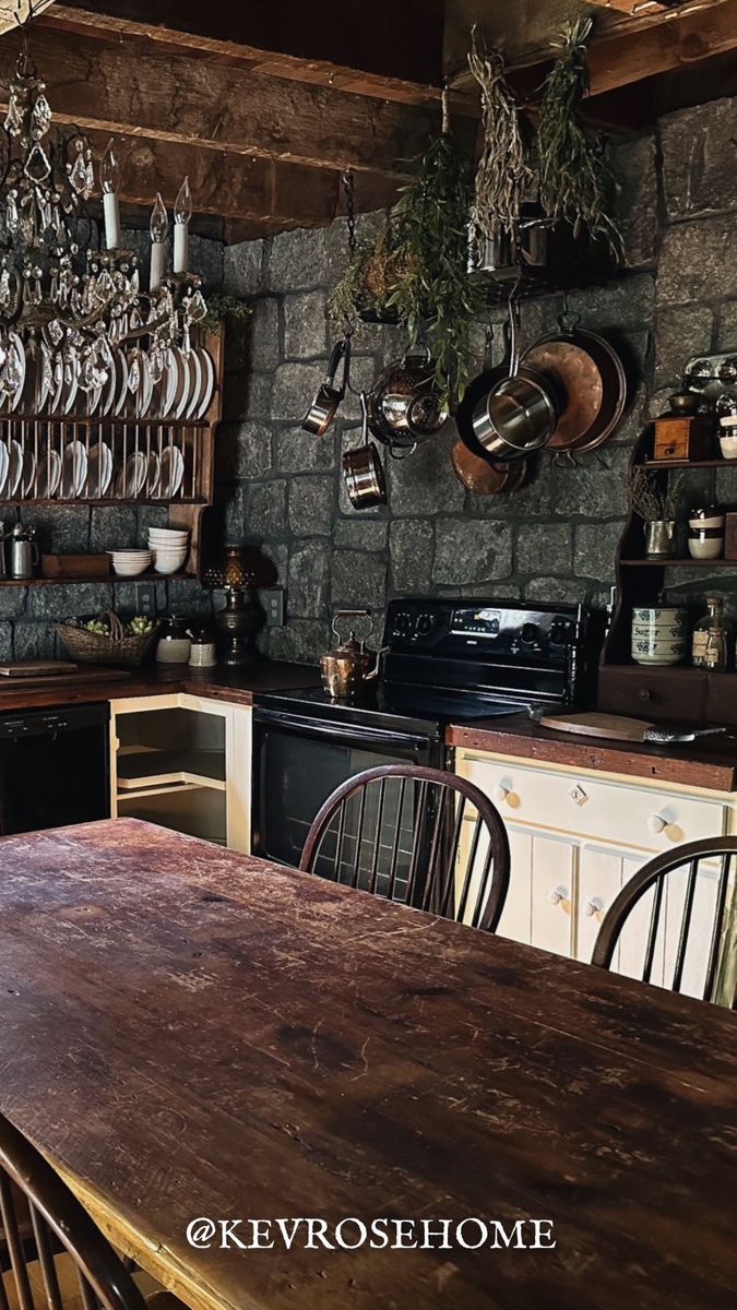 an old fashioned kitchen with stone walls and wooden table in the center, surrounded by hanging pots and pans