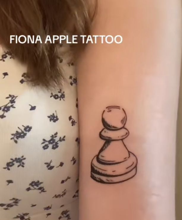 a woman's arm with a small tattoo of a chess piece on the wrist