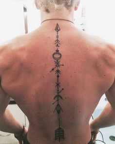 the back of a man with an arrow tattoo on his upper and lower back tattoos