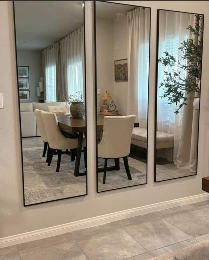 the reflection of a dining room table and chairs in two large mirrors on the wall