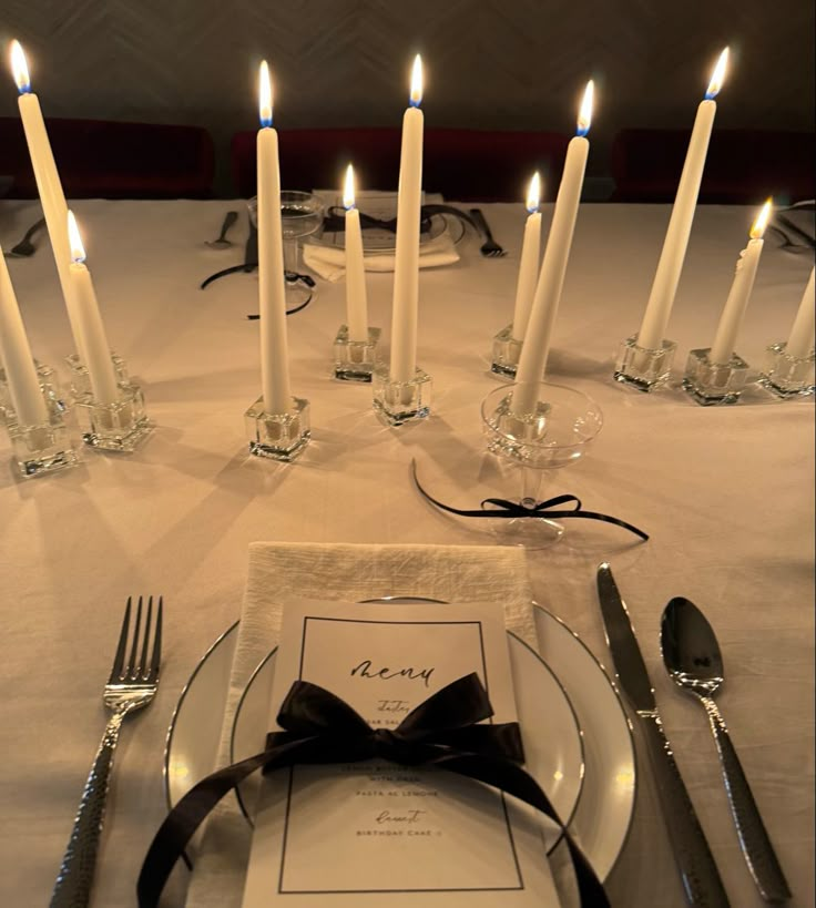 the place setting is set with silverware, candles and napkins for an elegant dinner