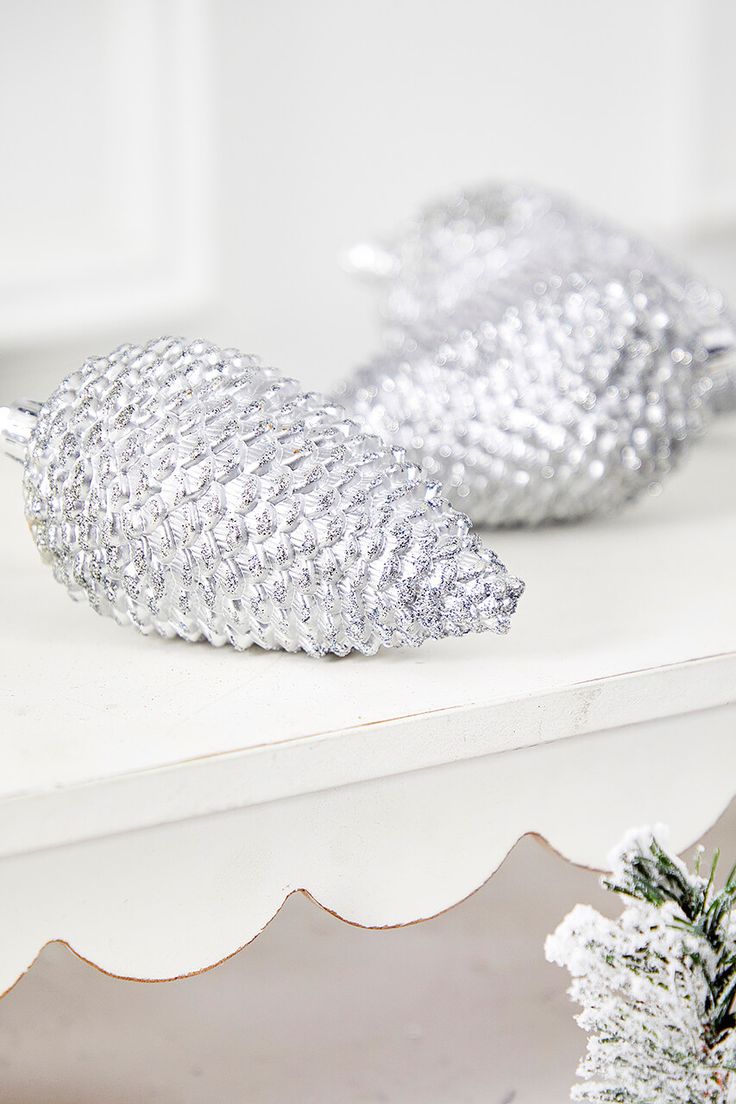 two shiny silver fish figurines sitting on top of a white shelf next to a christmas tree