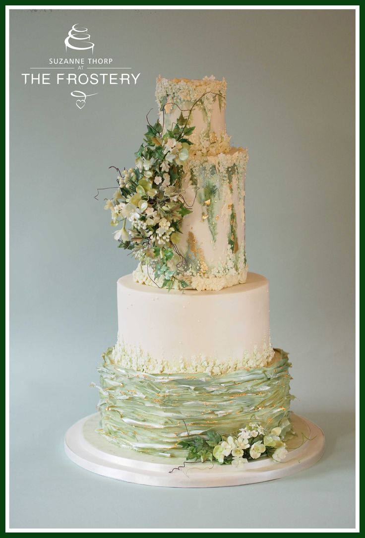 a three tiered cake with white flowers and greenery on top