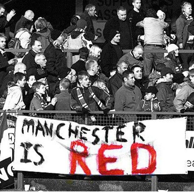 a group of people sitting in the stands at a soccer game with a banner that reads manchester is red