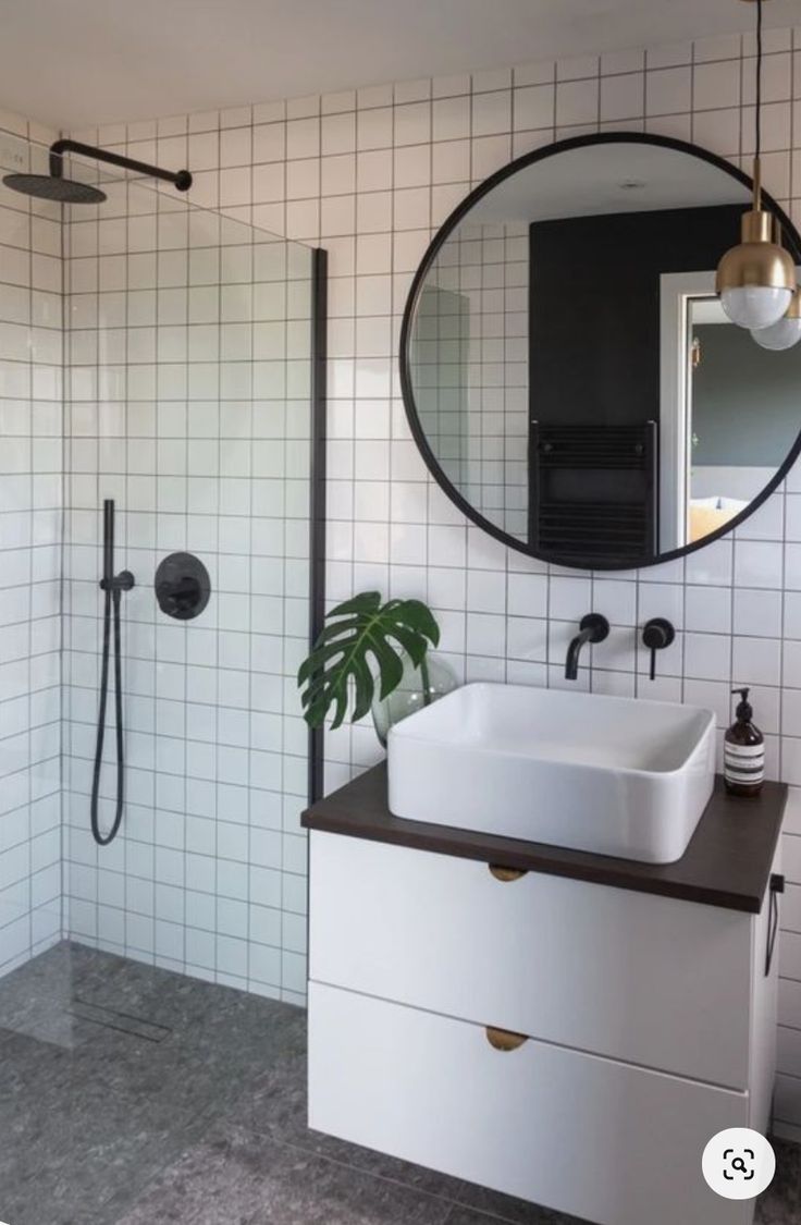 a white sink sitting under a round mirror in a bathroom