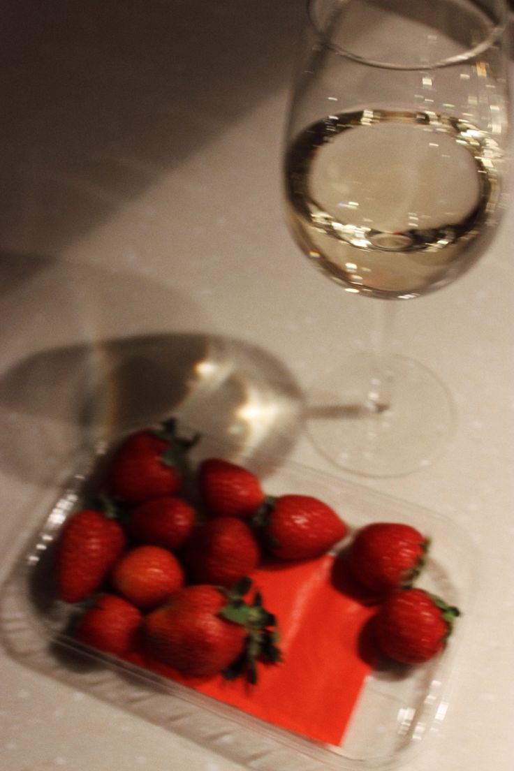 strawberries on a plate next to a glass of wine