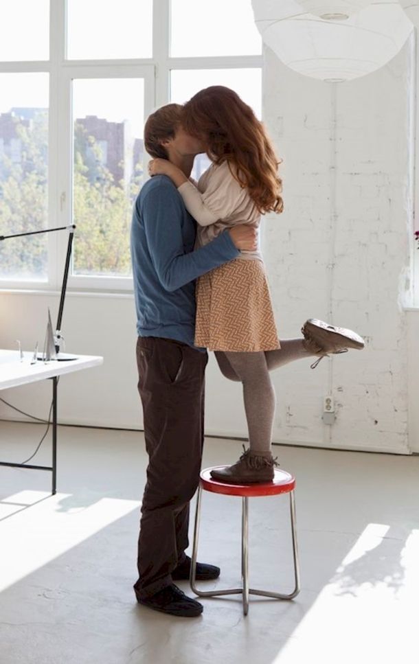 a man and woman kissing each other while standing in front of a window with the sun shining on them