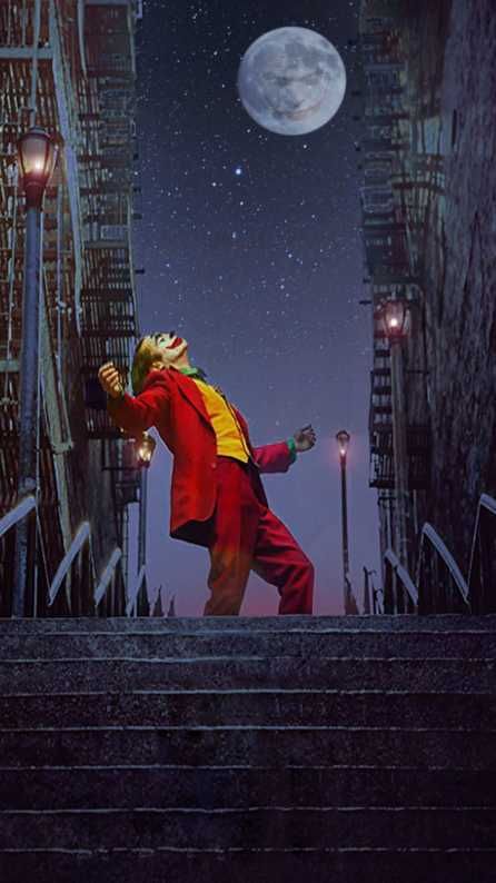 a man dressed in red and yellow is walking up some stairs at night with the moon behind him