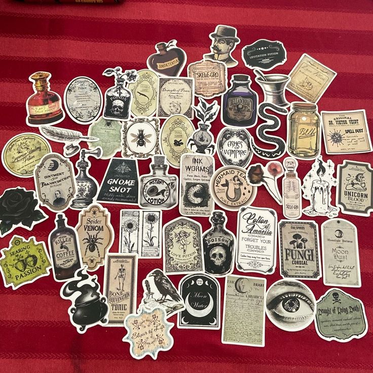 many different types and sizes of stickers on a red table cloth with a bottle of wine in the background