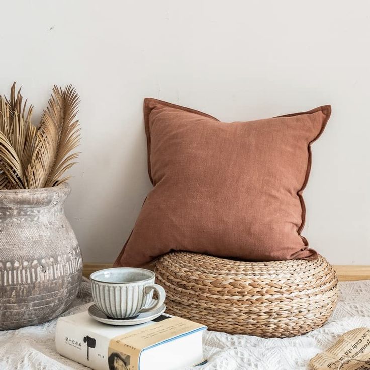 a coffee cup sitting on top of a bed next to a basket and bookcase