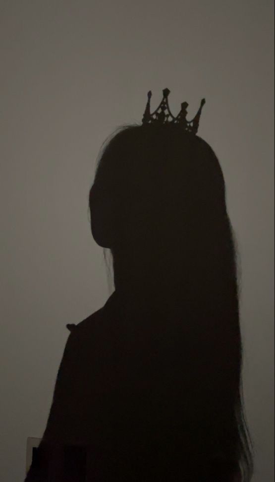 the silhouette of a woman with a crown on her head, against a foggy background