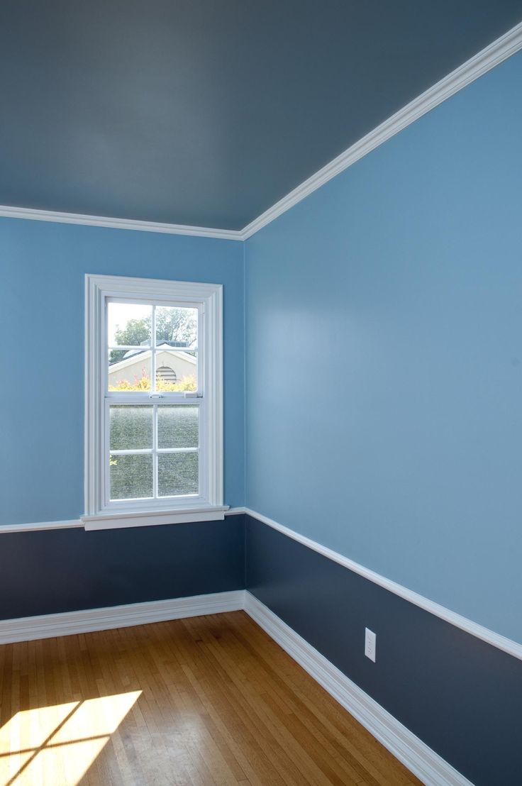 an empty room with blue walls and wood floors