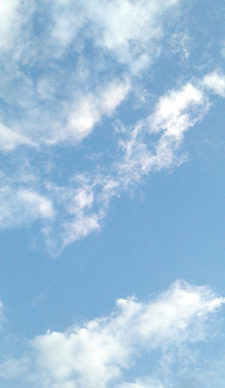 the airplane is flying high in the blue sky with white clouds above it and below