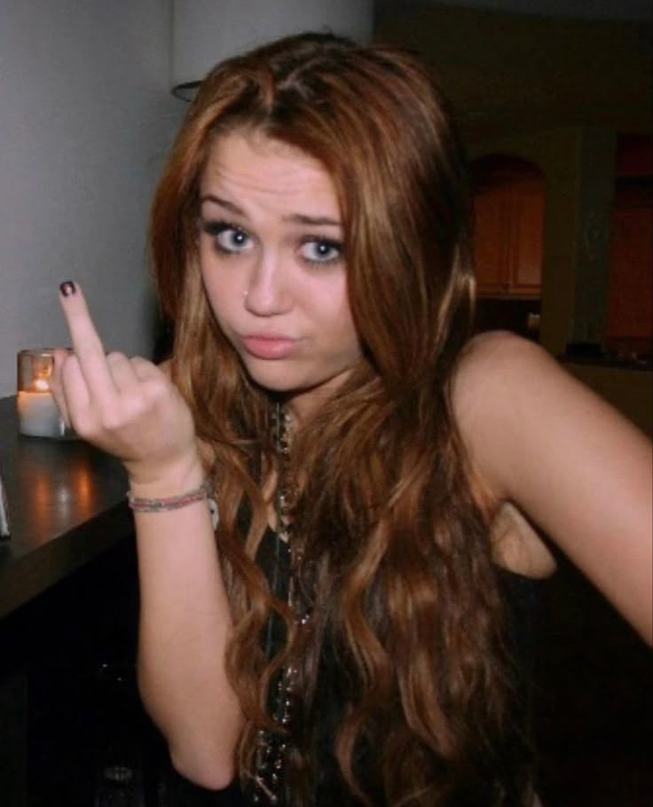 a woman with long red hair pointing at the camera