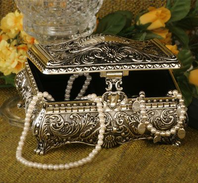 an ornate silver jewelry box with pearls on the bottom and side, sitting next to flowers