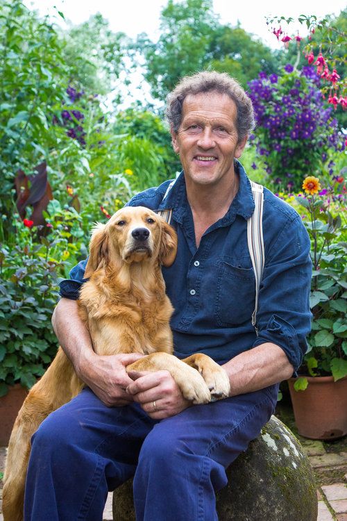 a man sitting on top of a rock holding a large brown dog in his lap