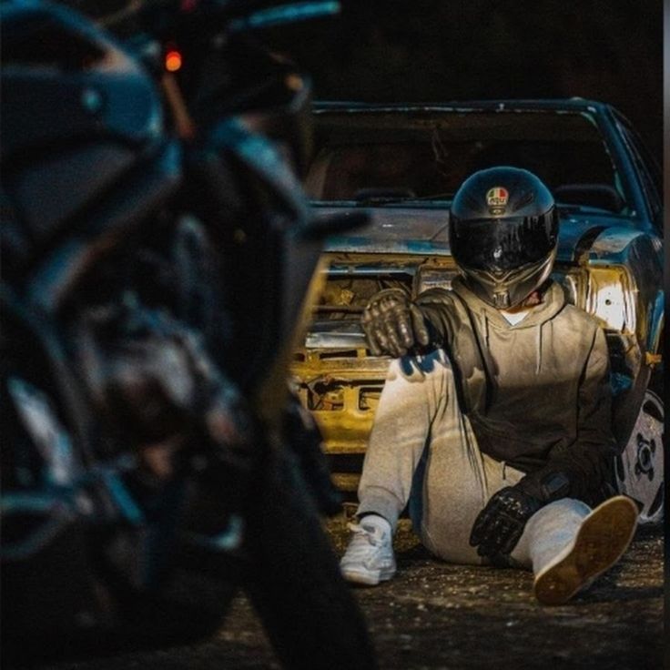 a man sitting on the ground next to a motorcycle