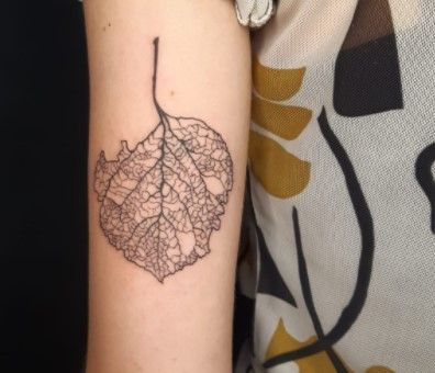 a woman's arm with a leaf tattoo on it