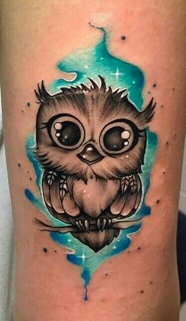 an owl tattoo on the thigh with blue watercolors and stars in the background