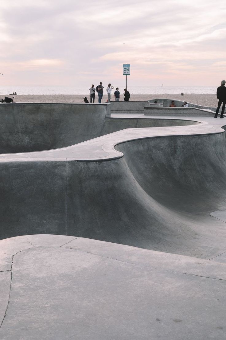 several skateboard ramps are shown with people standing on the top and one person sitting at the bottom