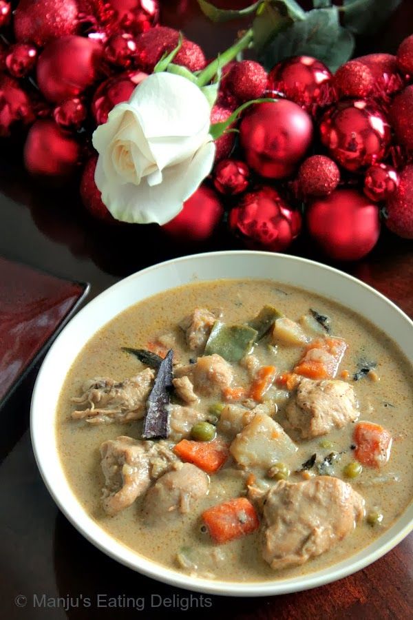 a white bowl filled with meat and vegetables next to red baubs on a table