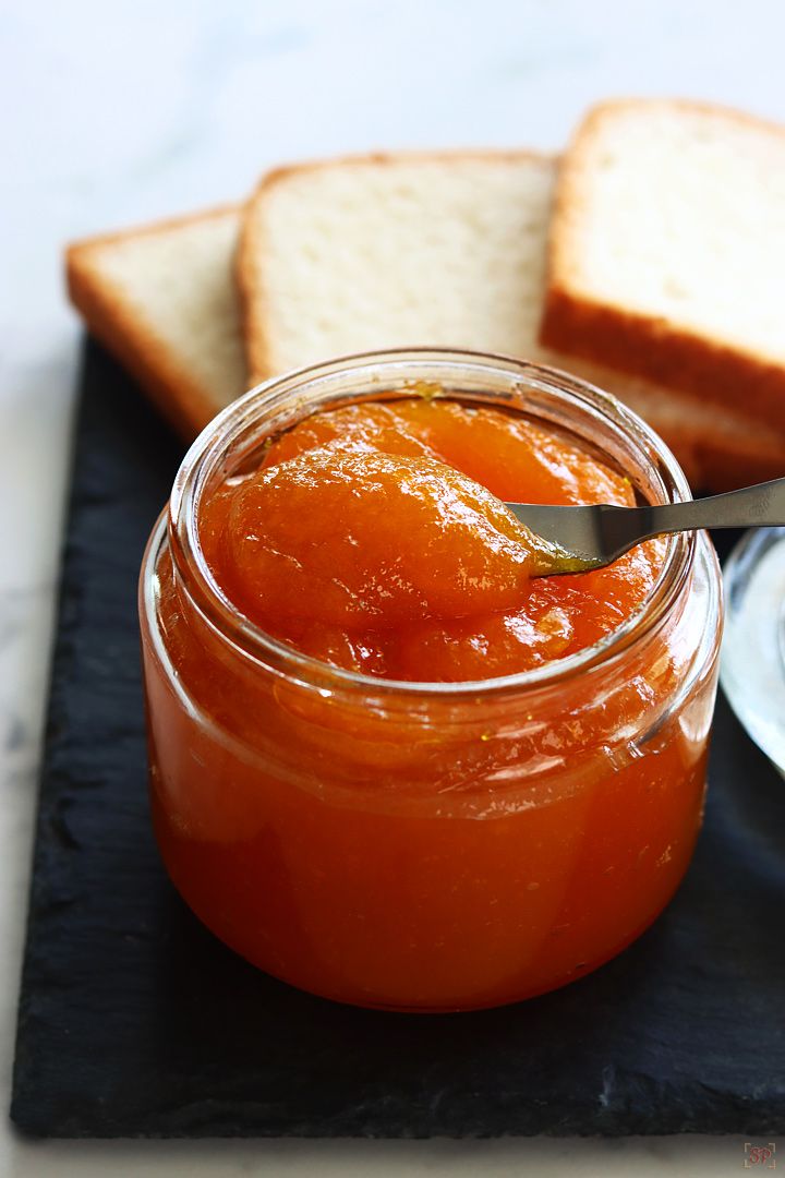 there is a jar of jam with bread on the side and a spoon in it