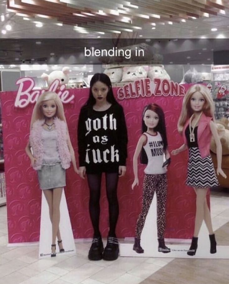 three barbie dolls are standing in front of a sign