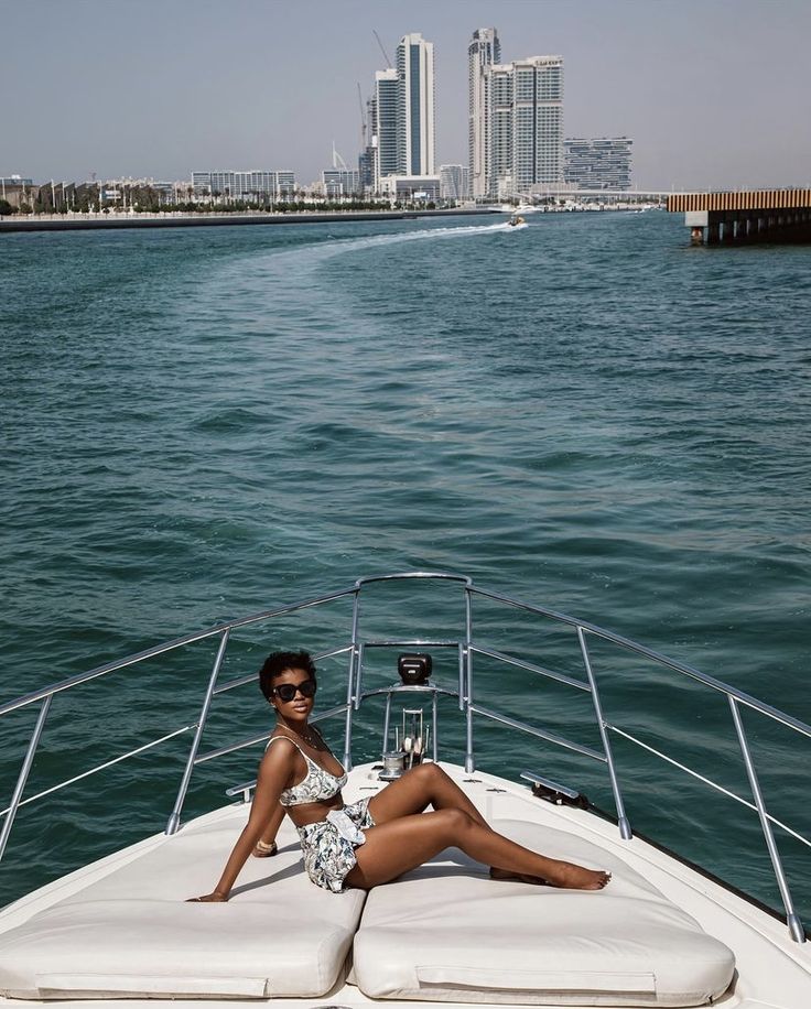 a woman is sitting on the back of a boat in the water with her legs crossed