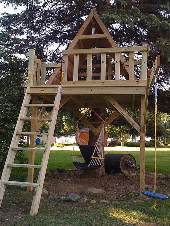 a wooden play structure with a ladder to the top and a tree house above it