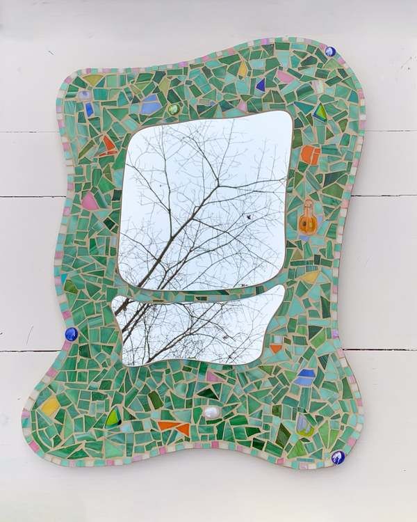 a mirror that is sitting on the side of a wall with a tree in it