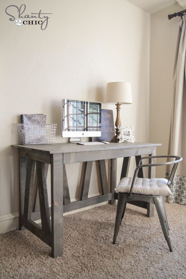 a wooden desk sitting next to a lamp on top of a carpeted floor in front of a white wall