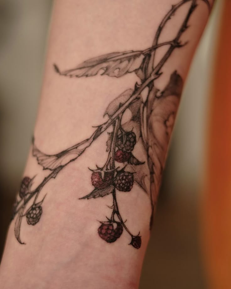 a close up of a person's arm with flowers and leaves tattooed on it