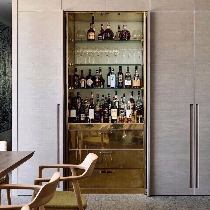 a bar with lots of bottles and glasses on the back wall, in front of an open door