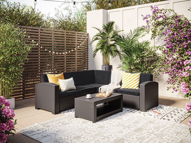 an outdoor living area with black furniture and purple flowers