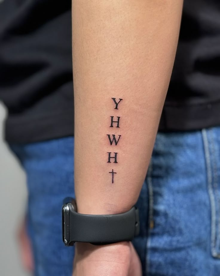 a person with a wrist tattoo that reads yhwh