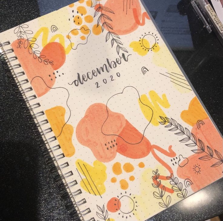 a notebook with an orange and yellow floral design on it, sitting on a table