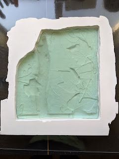 a white box with green frosting in it on top of a black countertop