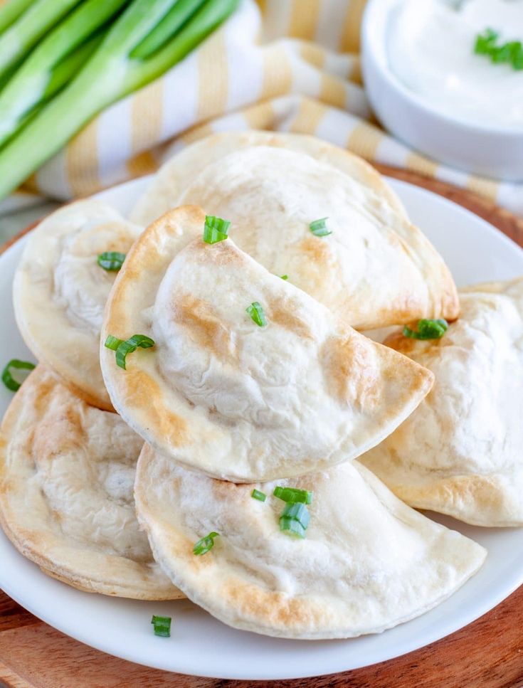 several pita breads on a white plate with asparagus in the background