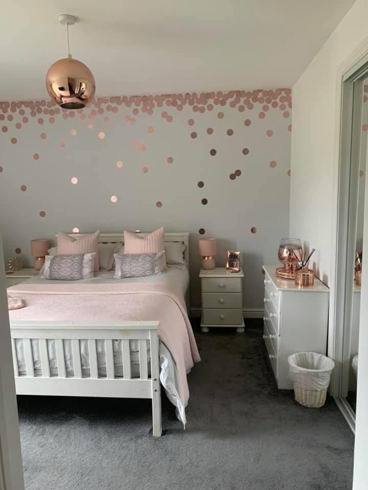 a white bed sitting in a bedroom next to a wall with polka dots on it