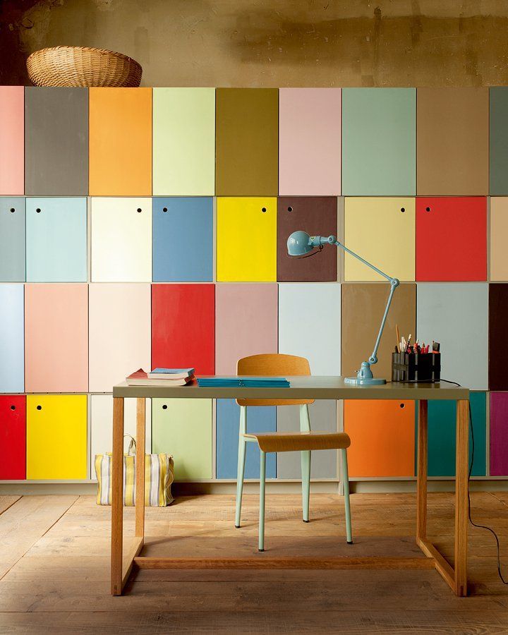 an office with multicolored tiles on the wall and wooden desk in front of it